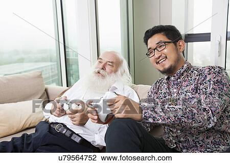 Portrait of grandson playing video game on sofa at home View Large Photo Image Stock Image - Portrait of grandson playing video game on sofa at home. Fotosearch