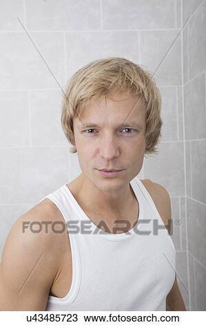 Stock Image - Portrait of handsome man standing in bathroom. Fotosearch