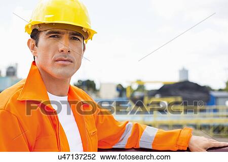 Portrait of handsome mid adult man wearing protective workwear at construction site View Large Photo Image Stock Image - Portrait of handsome mid adult man wearing protective workwear at construction site. Fotosearch
