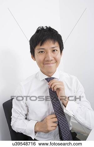 Portrait of happy businessman adjusting necktie at office View Large Photo Image Stock Photograph - Portrait of happy businessman adjusting necktie at office. Fotosearch