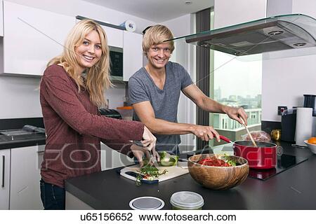 Stock Image - Portrait of happy Caucasian couple cooking together in kitchen. Fotosearch