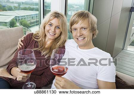 Portrait of happy couple with wine glasses in living room at home View Large Photo Image Stock Image - Portrait of happy couple with wine glasses in living room at home. Fotosearch