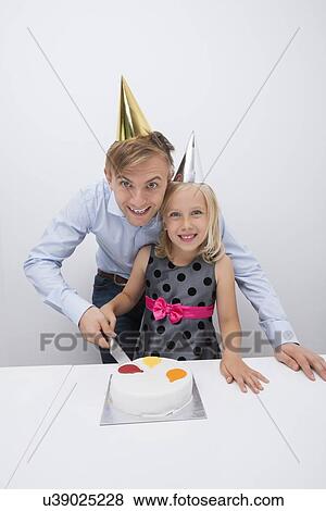 Portrait of happy father and daughter cutting birthday cake at table View Large Photo Image Stock Photo - Portrait of happy father and daughter cutting birthday cake at table. Fotosearch