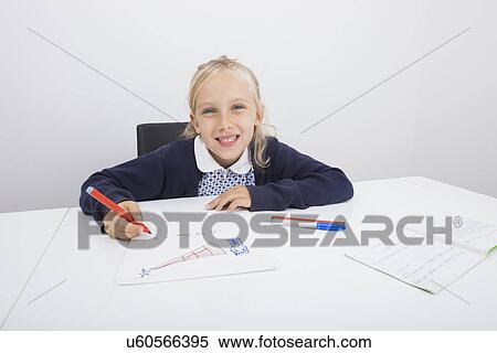 Stock Photography - Portrait of happy girl drawing on paper at table. Fotosearch