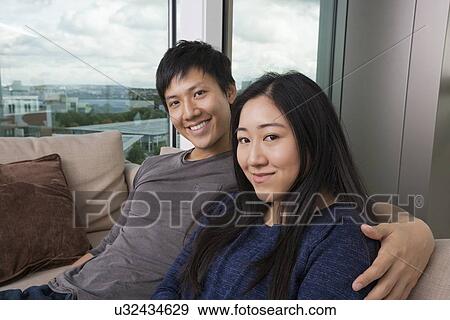 Stock Photo - Portrait of happy loving couple sitting on sofa at home. Fotosearch