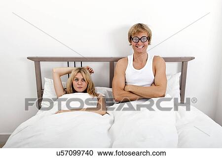 Portrait of happy man wearing retro glasses while sitting with woman in bed View Large Photo Image Stock Image - Portrait of happy man wearing retro glasses while sitting with woman in bed. Fotosearch