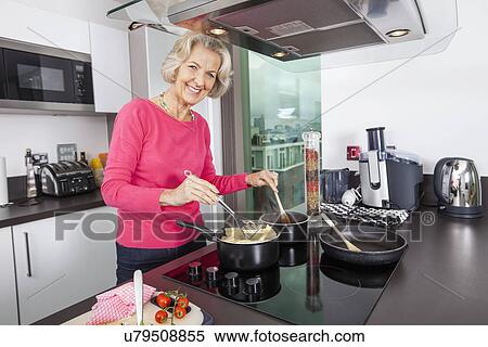 Portrait of happy senior woman cooking food at kitchen counter View Large Photo Image Stock Photography - Portrait of happy senior woman cooking food at kitchen counter. Fotosearch