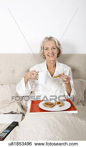 Portrait of happy senior woman having breakfast in bed View Large Photo Image Stock Photograph - Portrait of happy senior woman having breakfast in bed. Fotosearch