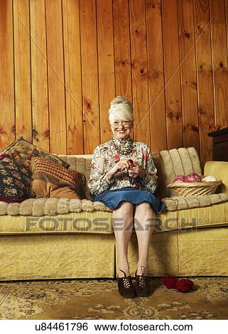 Portrait of happy senior woman knitting on sofa at home View Large Photo Image Stock Photograph - Portrait of happy senior woman knitting on sofa at home. Fotosearch