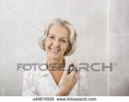 Portrait of happy senior woman spraying perfume in bathroom View Large Photo Image Stock Photography - Portrait of happy senior woman spraying perfume in bathroom. Fotosearch