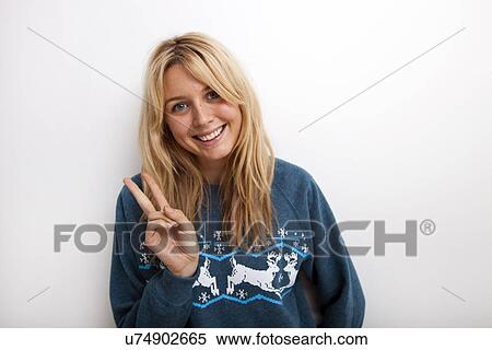 Stock Photography - Portrait of happy woman gesturing peace sign against white background. Fotosearch