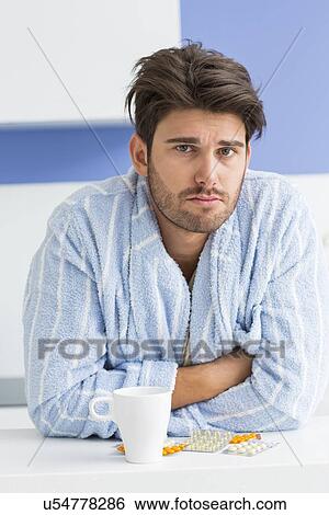Portrait of ill man with coffee mug and medicine leaning on kitchen counter View Large Photo Image Stock Photograph - Portrait of ill man with coffee mug and medicine leaning on kitchen counter. Fotosearch
