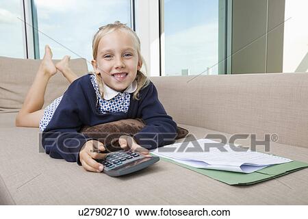 Portrait of little girl holding calculator while lying on sofa View Large Photo Image Stock Image - Portrait of little girl holding calculator while lying on sofa. Fotosearch