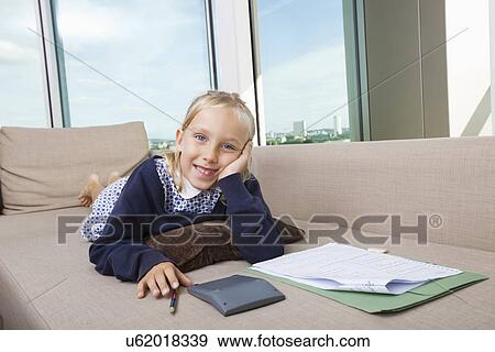 Portrait of little girl studying while lying on sofa View Large Photo Image Stock Photo - Portrait of little girl studying while lying on sofa. Fotosearch
