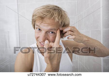 Portrait of man squeezing pimple on his forehead in bathroom View Large Photo Image Stock Photo - Portrait of man squeezing pimple on his forehead in bathroom. Fotosearch