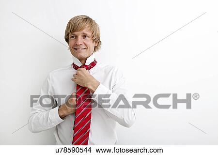 Portrait of mid adult businessman tying tie against white background View Large Photo Image Picture - Portrait of mid adult businessman tying tie against white background. Fotosearch