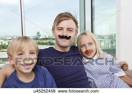 Portrait of mid adult man and children with artificial mustache at home View Large Photo Image Stock Photo - Portrait of mid adult man and children with artificial mustache at home. Fotosearch