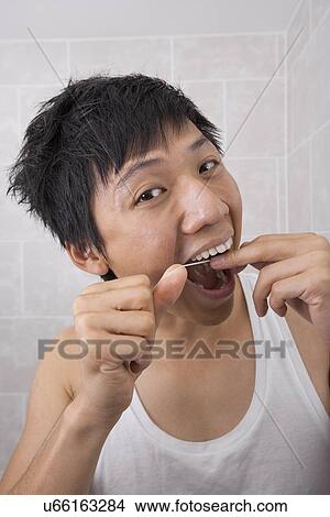 Portrait of mid adult man flossing his teeth in bathroom View Large Photo Image Picture - Portrait of mid adult man flossing his teeth in bathroom. Fotosearch