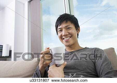 Portrait of mid adult man holding coffee cup in house View Large Photo Image Stock Photo - Portrait of mid adult man holding coffee cup in house. Fotosearch