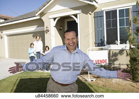 Stock Image - Portrait of mid-adult man in front of new house. Fotosearch