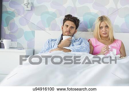Portrait of sad couple holding coffee mug and glass while relaxing on bed View Large Photo Image Stock Image - Portrait of sad couple holding coffee mug and glass while relaxing on bed. Fotosearch