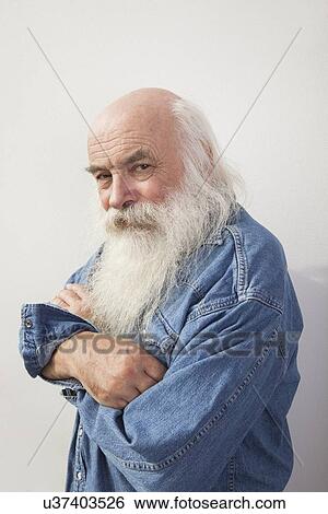 Stock Photograph - Portrait of senior man with arms crossed over gray background. Fotosearch