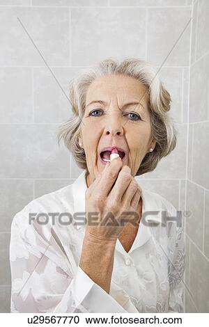 Portrait of senior woman applying lipstick in bathroom View Large Photo Image Stock Image - Portrait of senior woman applying lipstick in bathroom. Fotosearch