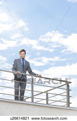 Portrait of smiling businessman at terrace railings against sky View Large Photo Image Stock Image - Portrait of smiling businessman at terrace railings against sky. Fotosearch