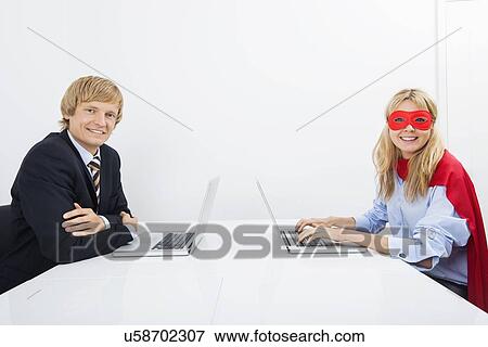 Portrait of smiling businessman with coworker in superhero costume using laptops at office View Large Photo Image Stock Photo - Portrait of smiling businessman with coworker in superhero costume using laptops at office. Fotosearch
