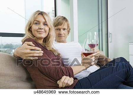 Portrait of smiling couple with wine glasses in living room at home View Large Photo Image Stock Photo - Portrait of smiling couple with wine glasses in living room at home. Fotosearch