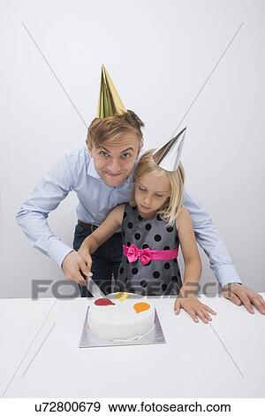 Portrait of smiling father cutting birthday cake with daughter at table View Large Photo Image Stock Photo - Portrait of smiling father cutting birthday cake with daughter at table. Fotosearch