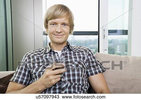 Portrait of smiling mid-adult man with glass of drink on sofa at home View Large Photo Image Stock Image - Portrait of smiling mid-adult man with glass of drink on sofa at home. Fotosearch