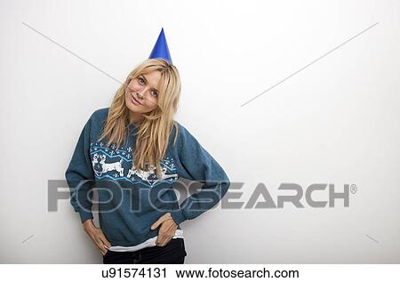 Portrait of woman in sweater wearing party hat against white background View Large Photo Image Stock Image - Portrait of woman in sweater wearing party hat against white background. Fotosearch