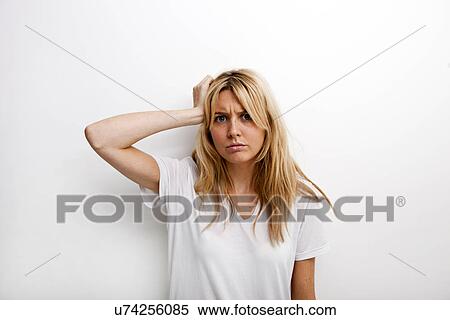 Portrait of worried woman with hand in hair against white background View Large Photo Image Stock Photography - Portrait of worried woman with hand in hair against white background. Fotosearch
