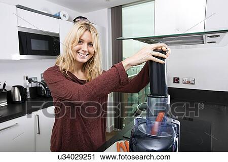 Portrait of young blond woman using juicer for juicing carrots in kitchen View Large Photo Image Stock Image - Portrait of young blond woman using juicer for juicing carrots in kitchen. Fotosearch