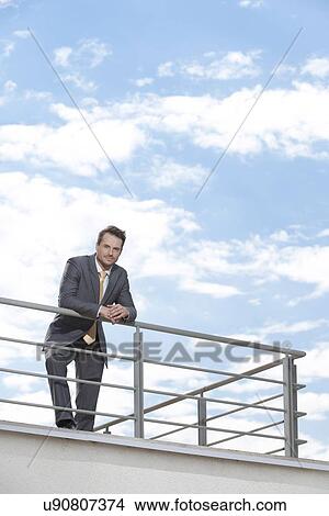 Picture - Portrait of young businessman leaning on terrace railings. Fotosearch