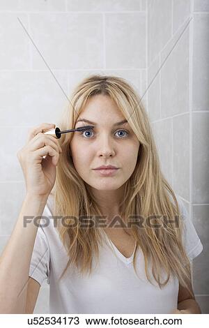 Portrait of young woman applying mascara in bathroom View Large Photo Image Stock Image - Portrait of young woman applying mascara in bathroom. Fotosearch
