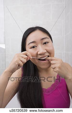 Portrait of young woman flossing her teeth in bathroom View Large Photo Image Stock Photo - Portrait of young woman flossing her teeth in bathroom. Fotosearch