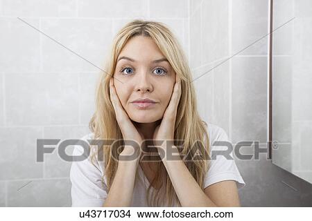 Portrait of young woman touching cheeks in bathroom View Large Photo Image Picture - Portrait of young woman touching cheeks in bathroom. Fotosearch