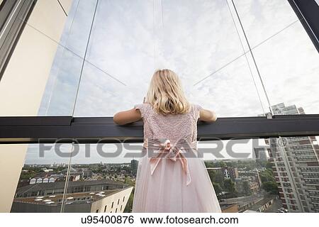 Rear view of girl looking through window View Large Photo Image Stock Photograph - Rear view of girl looking through window. Fotosearch