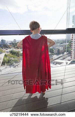 Picture - Rear view of little boy in superhero costume at home. Fotosearch