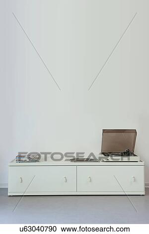 Stock Image - Record player on cabinet against wall. Fotosearch