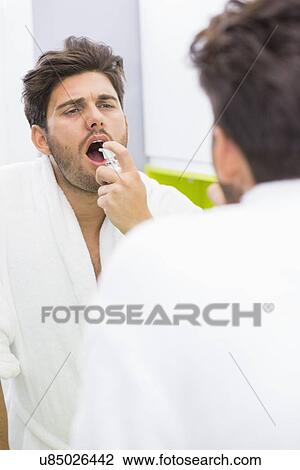 Reflection of man spraying medicine in mouth View Large Photo Image Stock Image - Reflection of man spraying medicine in mouth. Fotosearch