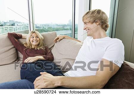 Relaxed couple looking at each other on sofa at home View Large Photo Image Picture - Relaxed couple looking at each other on sofa at home. Fotosearch