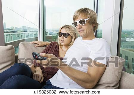 Relaxed couple wearing 3D glasses and watching TV at home View Large Photo Image Stock Image - Relaxed couple wearing 3D glasses and watching TV at home. Fotosearch