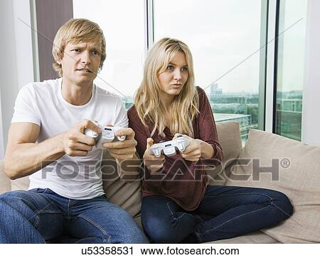 Relaxed young couple playing video game in living room at home View Large Photo Image Stock Image - Relaxed young couple playing video game in living room at home. Fotosearch