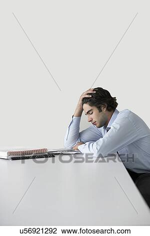 Sad young businessman leaning on desk in office View Large Photo Image Stock Image - Sad young businessman leaning on desk in office. Fotosearch