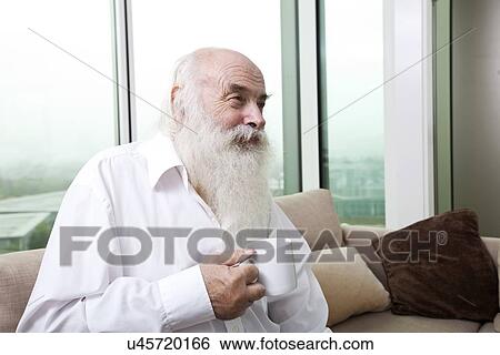 Stock Photograph - Senior man holding coffee cup at home. Fotosearch