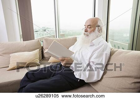 Senior man reading book on sofa in house View Large Photo Image Stock Photography - Senior man reading book on sofa in house. Fotosearch