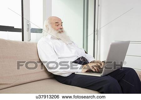 Stock Photograph - Senior man reading newspaper in house. Fotosearch